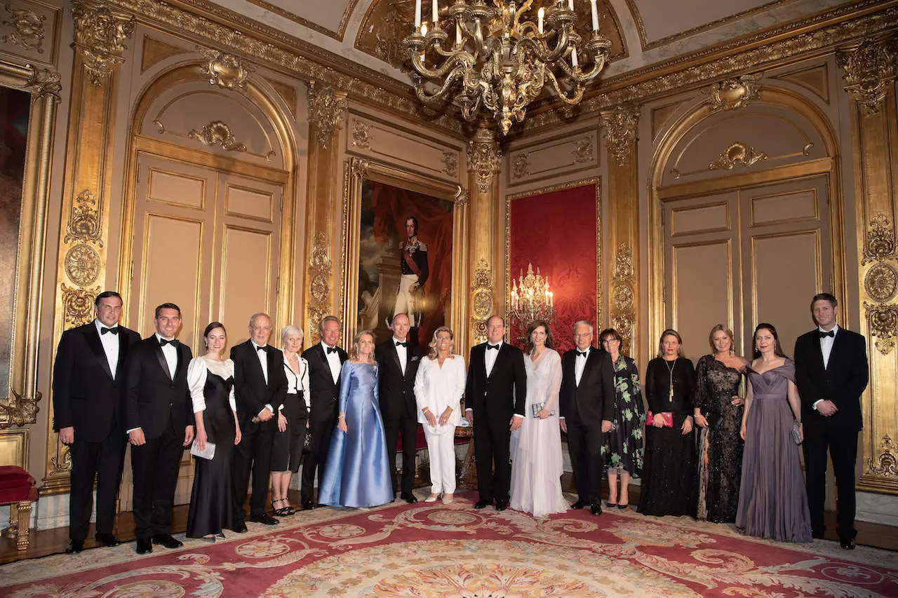 Un groupe d’invités en tenue de soirée posant dans un salon doré du palais d’Egmont