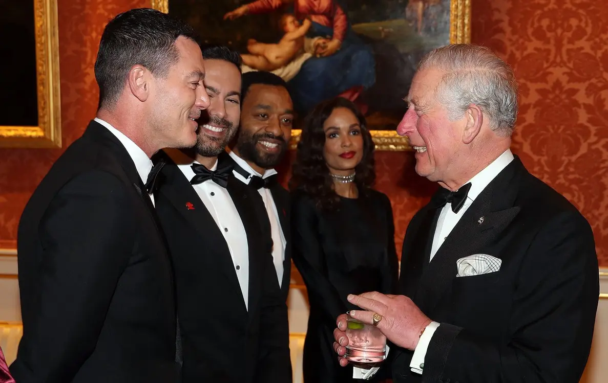 Le prince Charles discutant avec des invités en tenue de soirée, parmi lesquels des acteurs et des footballeurs
