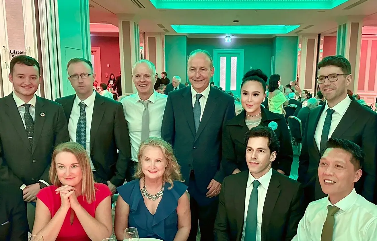 Micheál Martin et Jessica Chaijaya avec d’autres invités, debout et assis autour d’une table lors d’un dîner
