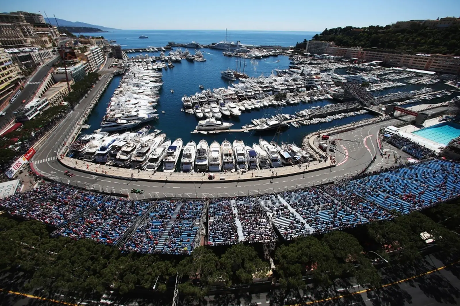 Vue aérienne du port de Monaco rempli de yachts, entouré du circuit du Grand Prix et de ses tribunes