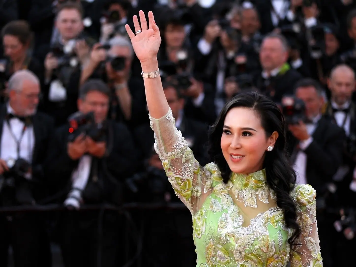 Jessica Chaijaya salue sur le tapis rouge, devant une foule de photographes