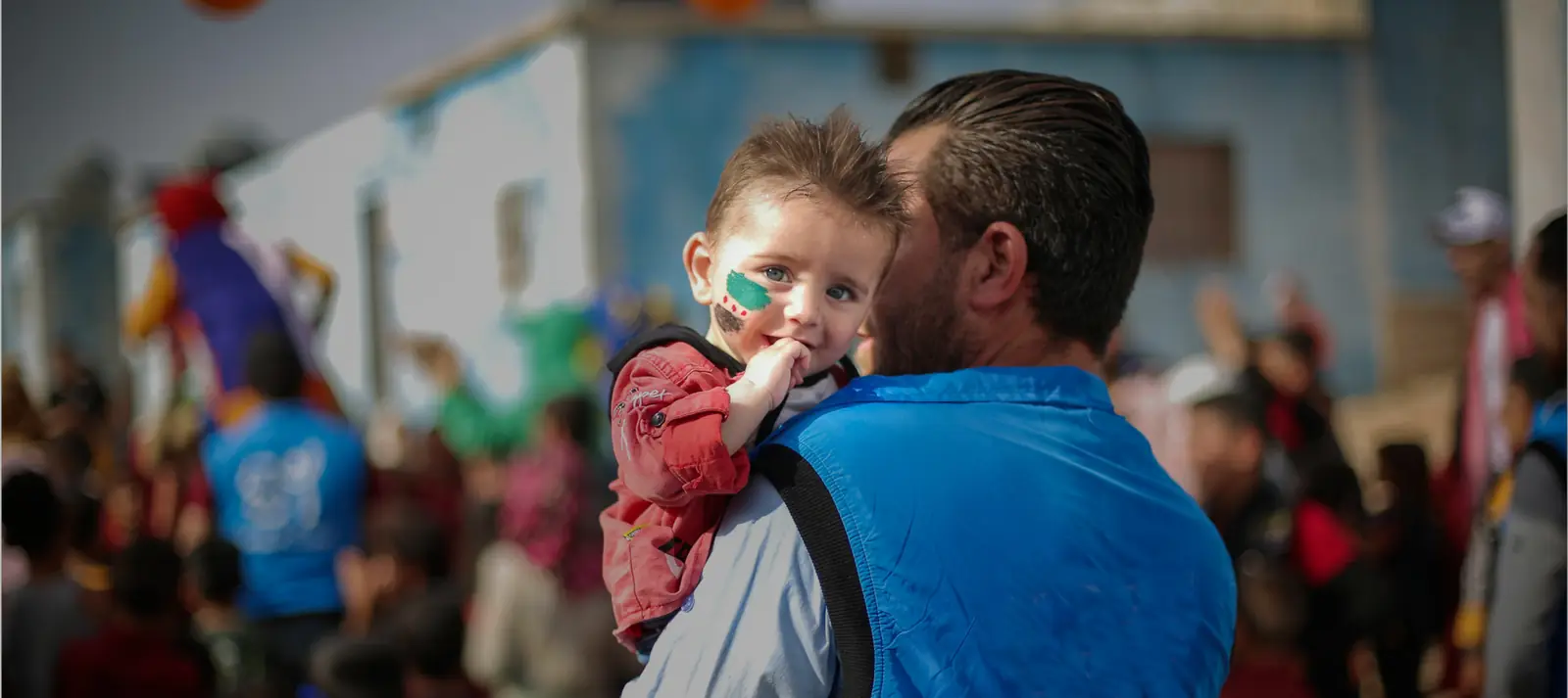 A rescue worker holds a smiling young child in a crowd