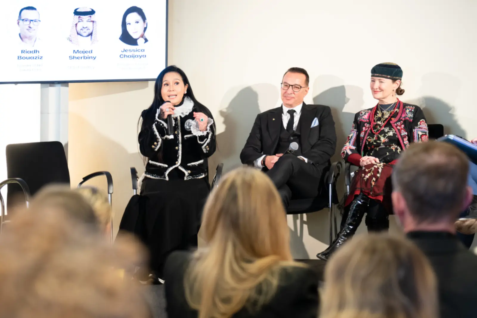 Jessica Chaijaya parlant au micro lors d’une table ronde, deux autres intervenants assis à ses côtés