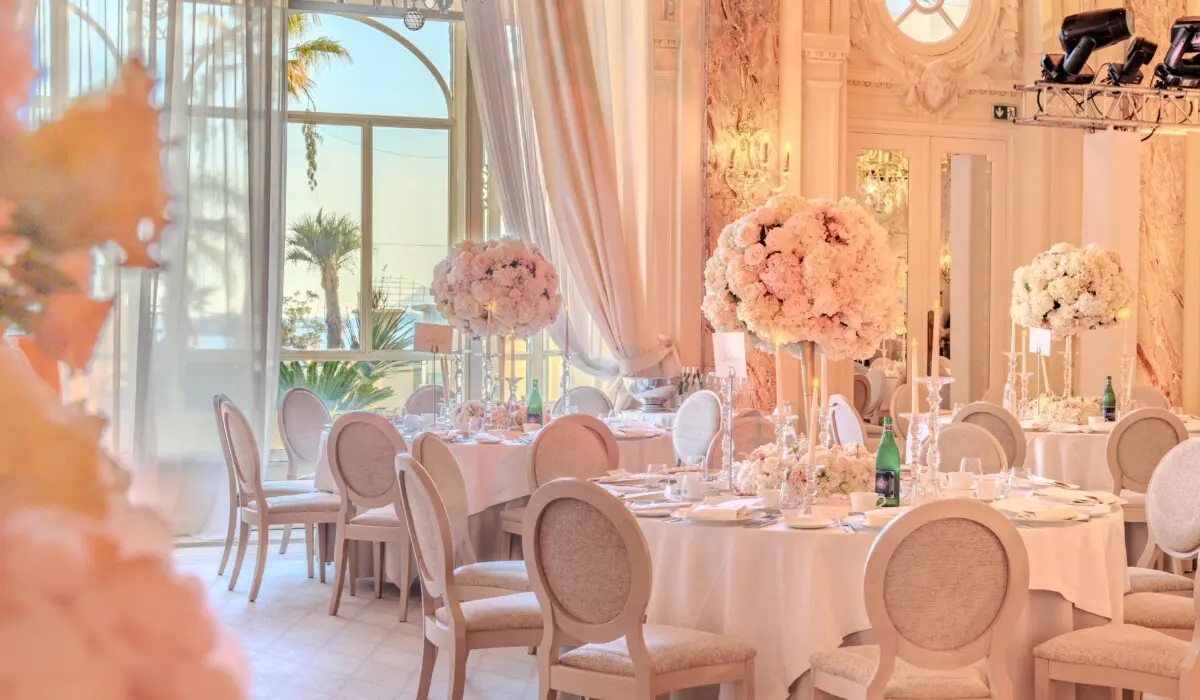 Tables rondes dressées avec des fleurs blanches et des lustres dans le Grand Salon du Carlton Cannes