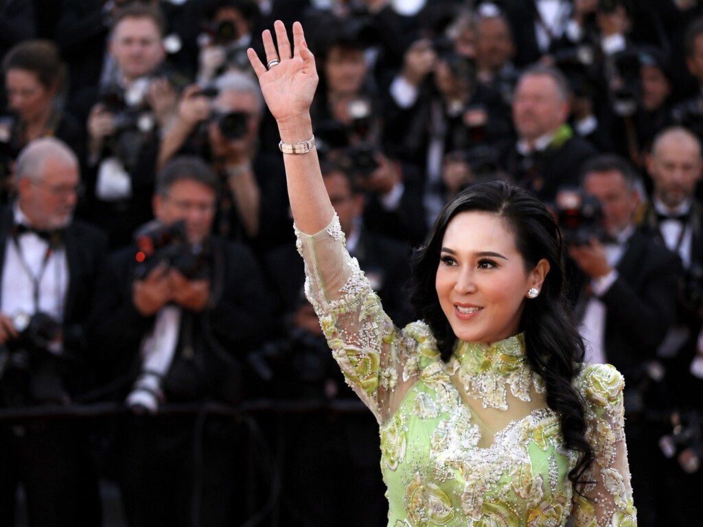 Jessica Chaijaya waves to the crowd on the red carpet at the 79th Cannes Film Festival, photographers visible behind her